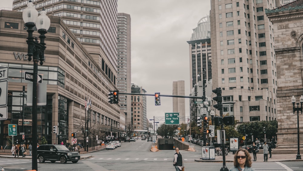 people walking on pathway near buildings and different vehicles on road during daytime