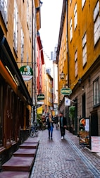 A charming cobblestone street lined with historic buildings and vibrant market stalls in a cultural city.