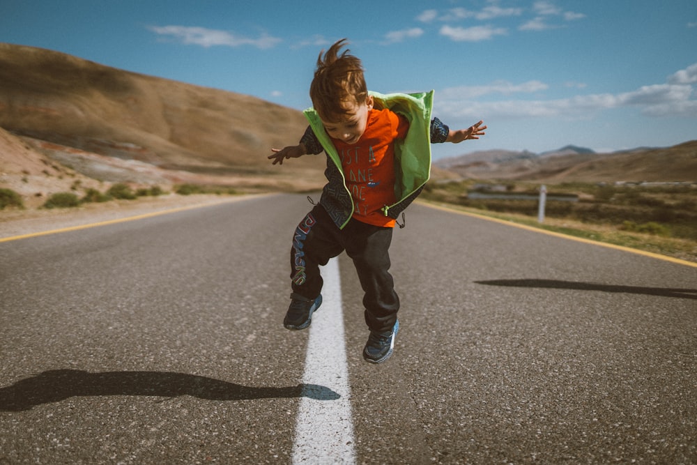 Um menino está pulando no ar em uma estrada