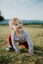 photo of baby on hands and knees trying to stand up on grass