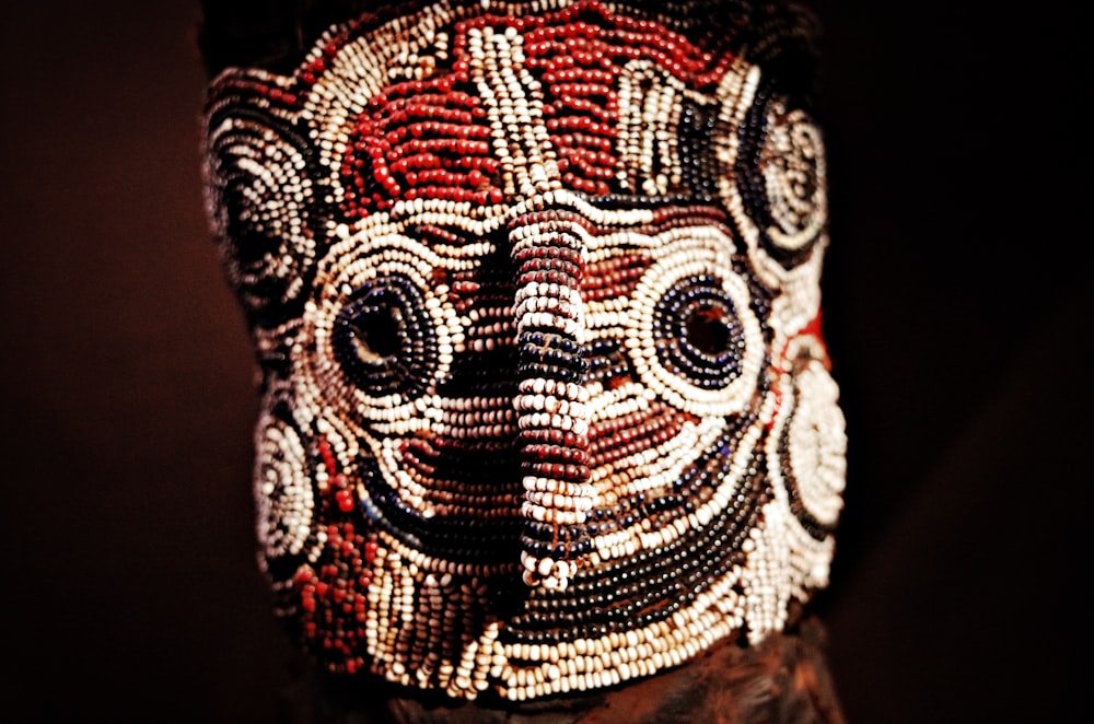a close up of a person wearing a beaded mask