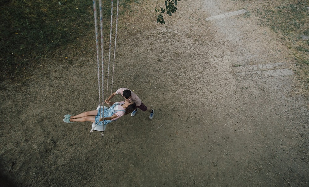 woman riding on swing beside man close-up photography
