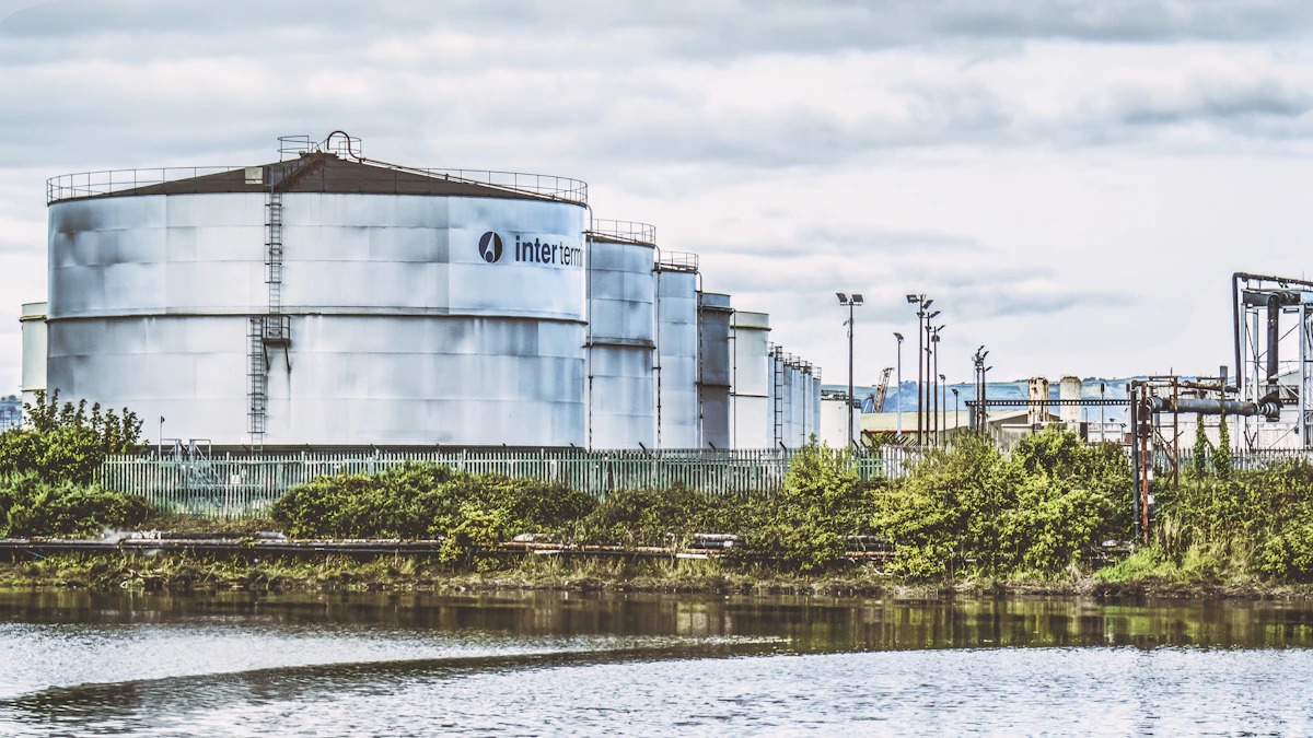 Chemical tank farm with large cylindrical storage tanks beside water, representing bulk liquid chemical storage