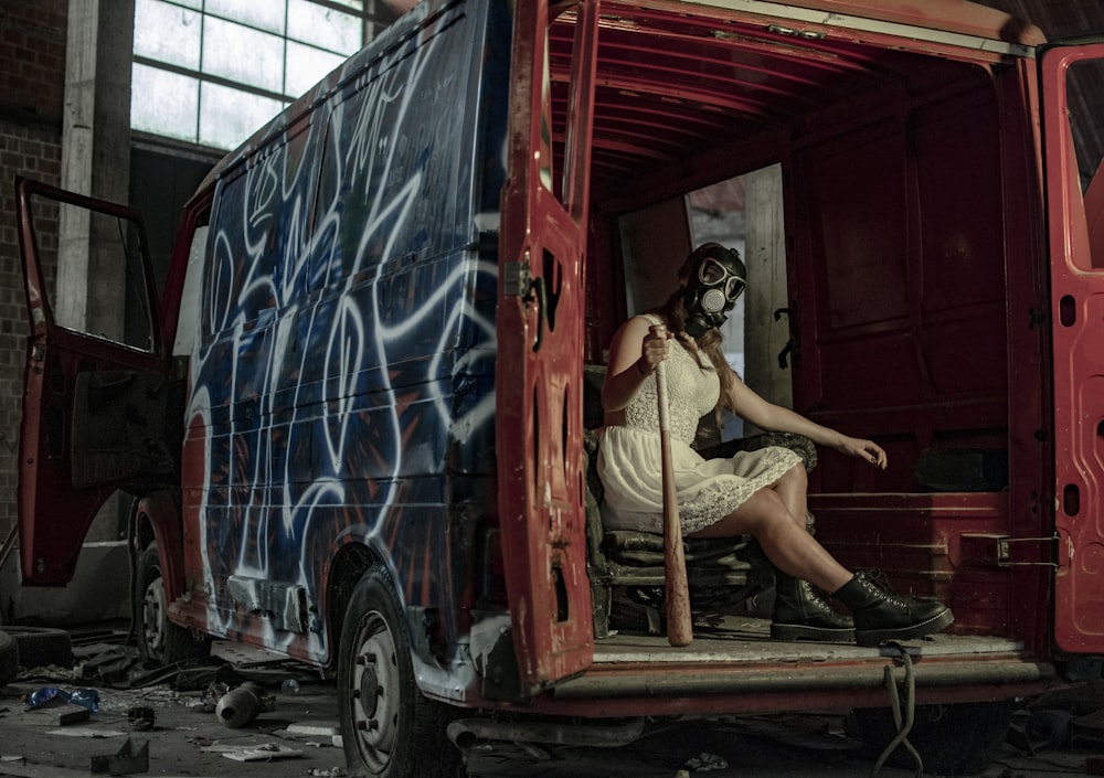 woman sitting in van while holding baseball bat