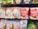 Various packaged snacks and candies are displayed on a store shelf. The packages feature colorful designs with images of fruits, beverages, and cartoon characters. The text on the packaging is in Japanese, with prominent depictions of strawberries, matcha, and milk tea.