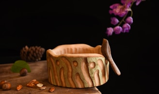 Close-up of a beautifully carved wooden bowl resting on a rustic table.