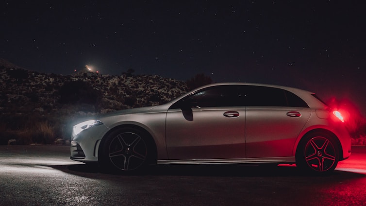 A sleek green and black hybrid car parked under a starry night sky with subtle stardust effects.