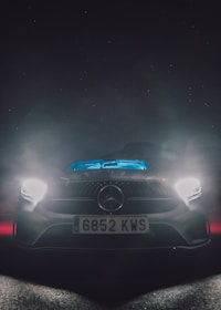 A sleek car illuminated by vibrant LED headlights on a dark road.