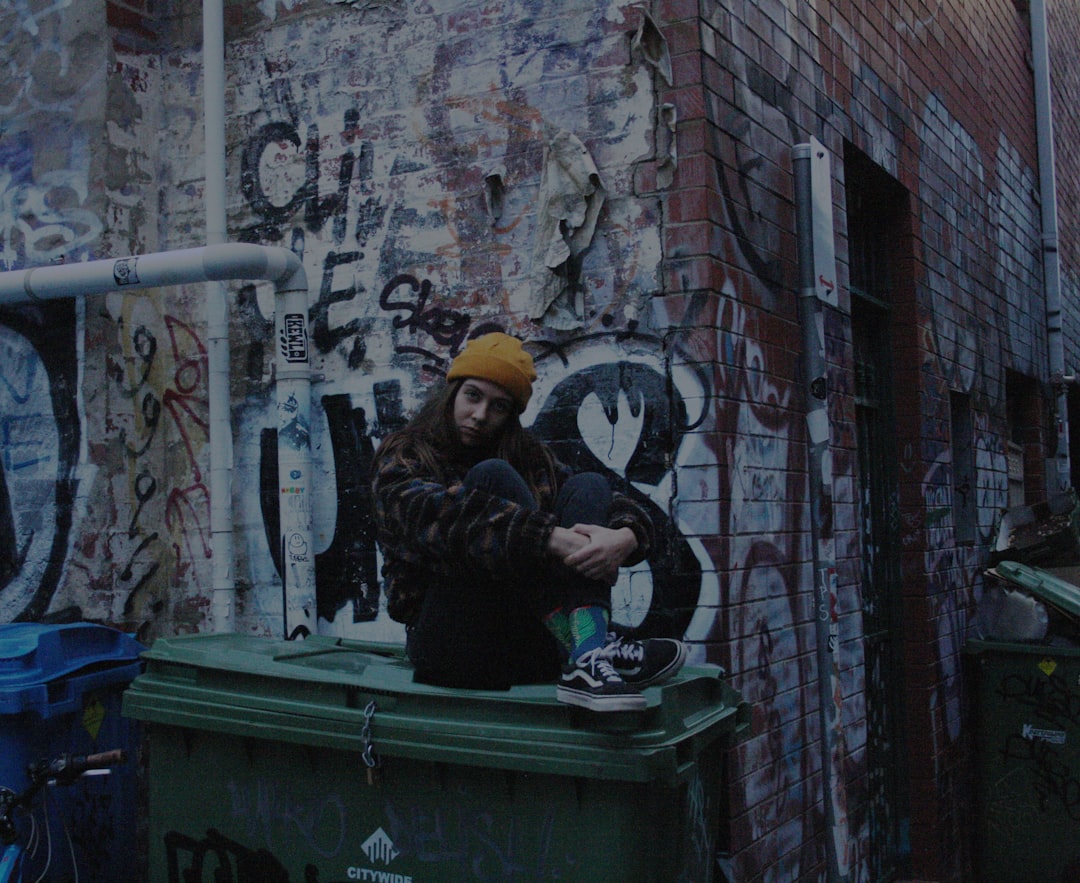 woman sitting on plastic trash bin