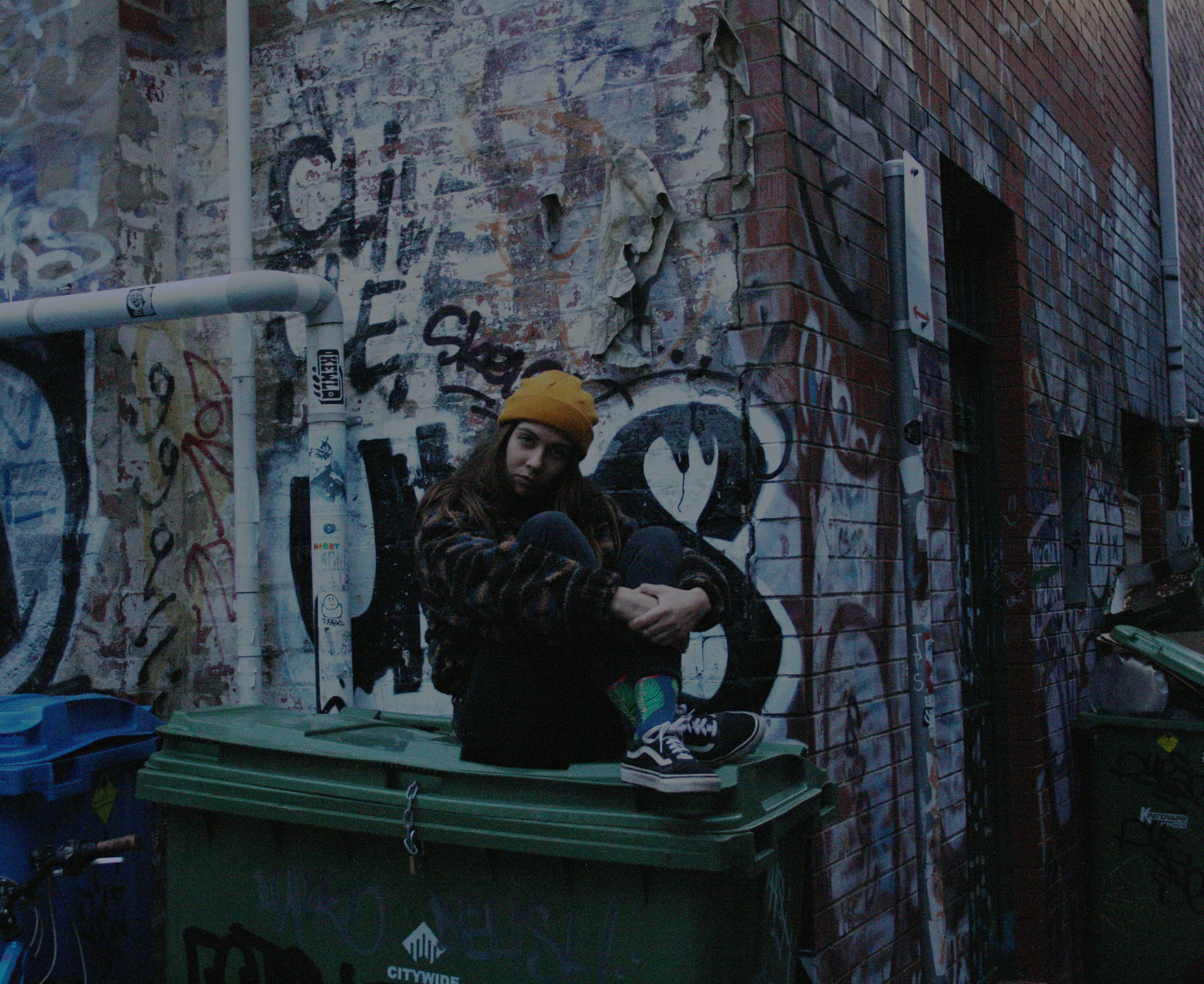 woman sitting on plastic trash bin