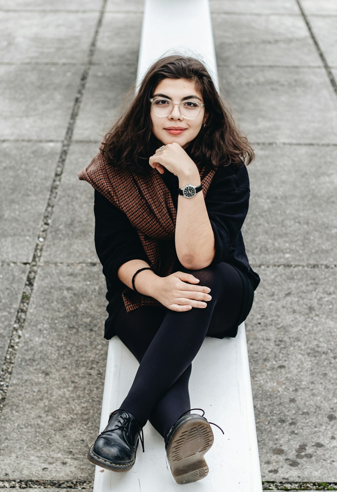 woman sits on concrete pavement near outdoor during daytime