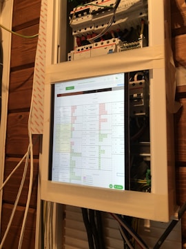 Close-up of a PLC and SCADA system setup inside a wall-mounted steel panel.