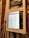 A close-up view of an electrical panel with a digital screen displaying a spreadsheet. The panel is secured with masking tape, and various colored wires are visible. The wooden wall in the background provides a rustic contrast to the modern equipment.
