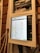 A close-up view of an electrical panel with a digital screen displaying a spreadsheet. The panel is secured with masking tape, and various colored wires are visible. The wooden wall in the background provides a rustic contrast to the modern equipment.
