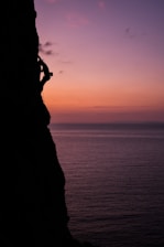 A dramatic shot of a climber scaling a jagged cliff at sunset in Australia.
