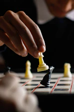 Close-up of a chessboard with a hand moving a knight piece symbolizing strategic financial planning.