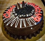 A rich chocolate cake with vibrant floral decorations and a hand-piped message for a special occasion.
