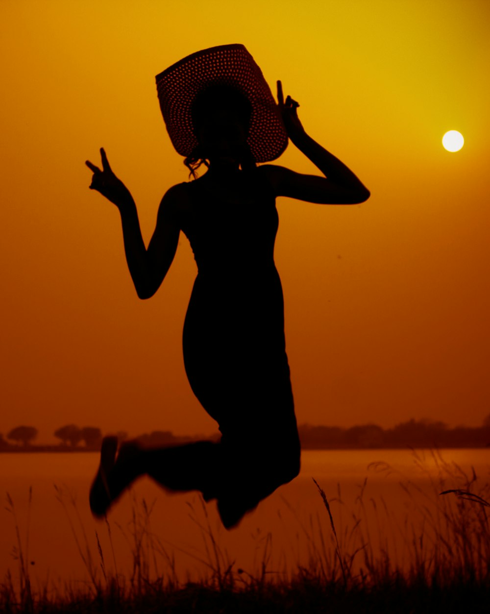 woman in hat jumping during golden hour