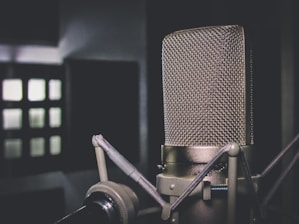 Close-up of a vintage microphone on stage with blurred audience lights.