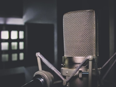 A close-up of hands holding a vintage microphone in a softly lit recording studio.