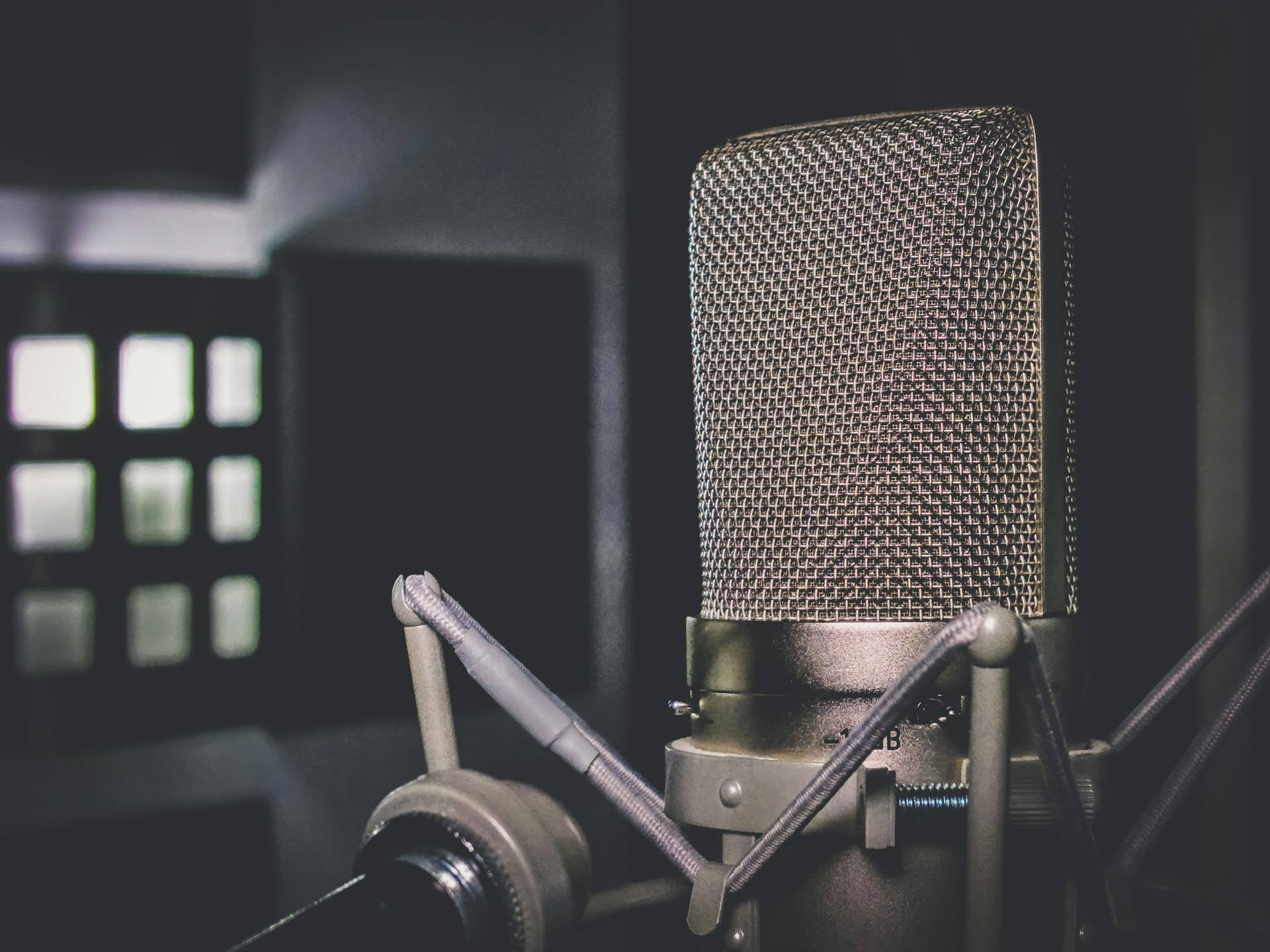 An artistic shot of a vintage microphone with a blurred audience in the background.
