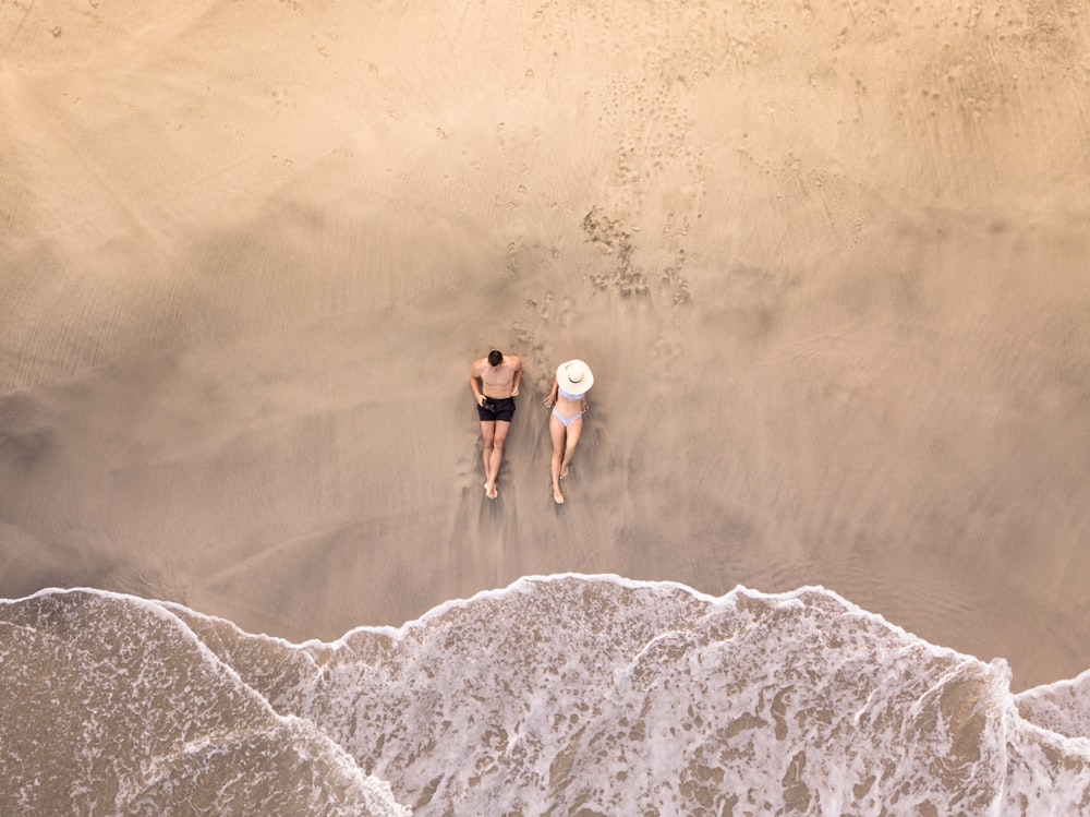 man and woman lying on seashore during daytime