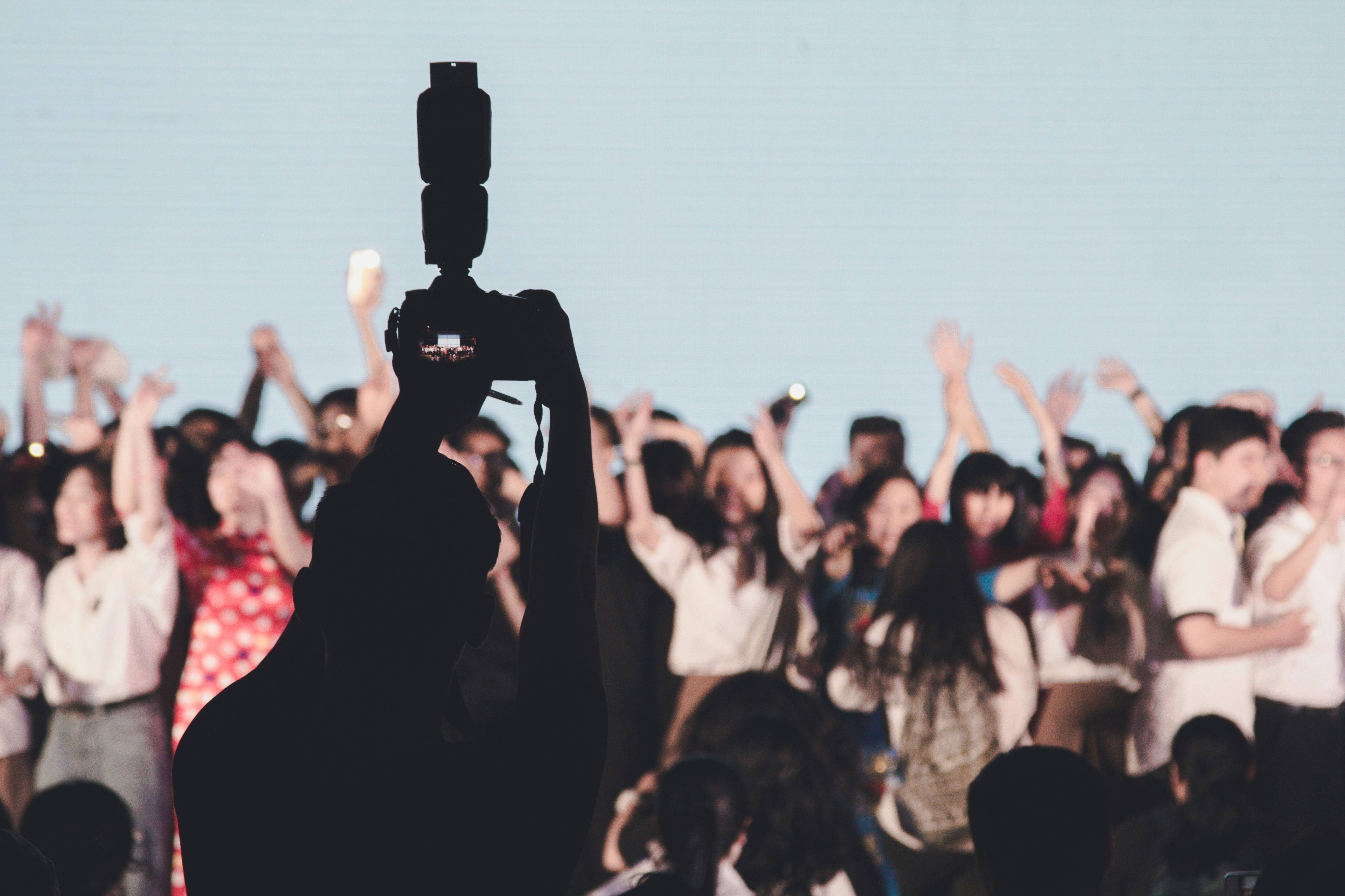 A silhouette of a political leader speaking into a microphone with blurred crowd in the background, representing public interaction and accountability.