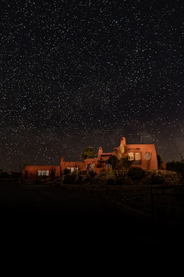 Cozy chalet exterior with warm lighting and desert landscape at sunset.