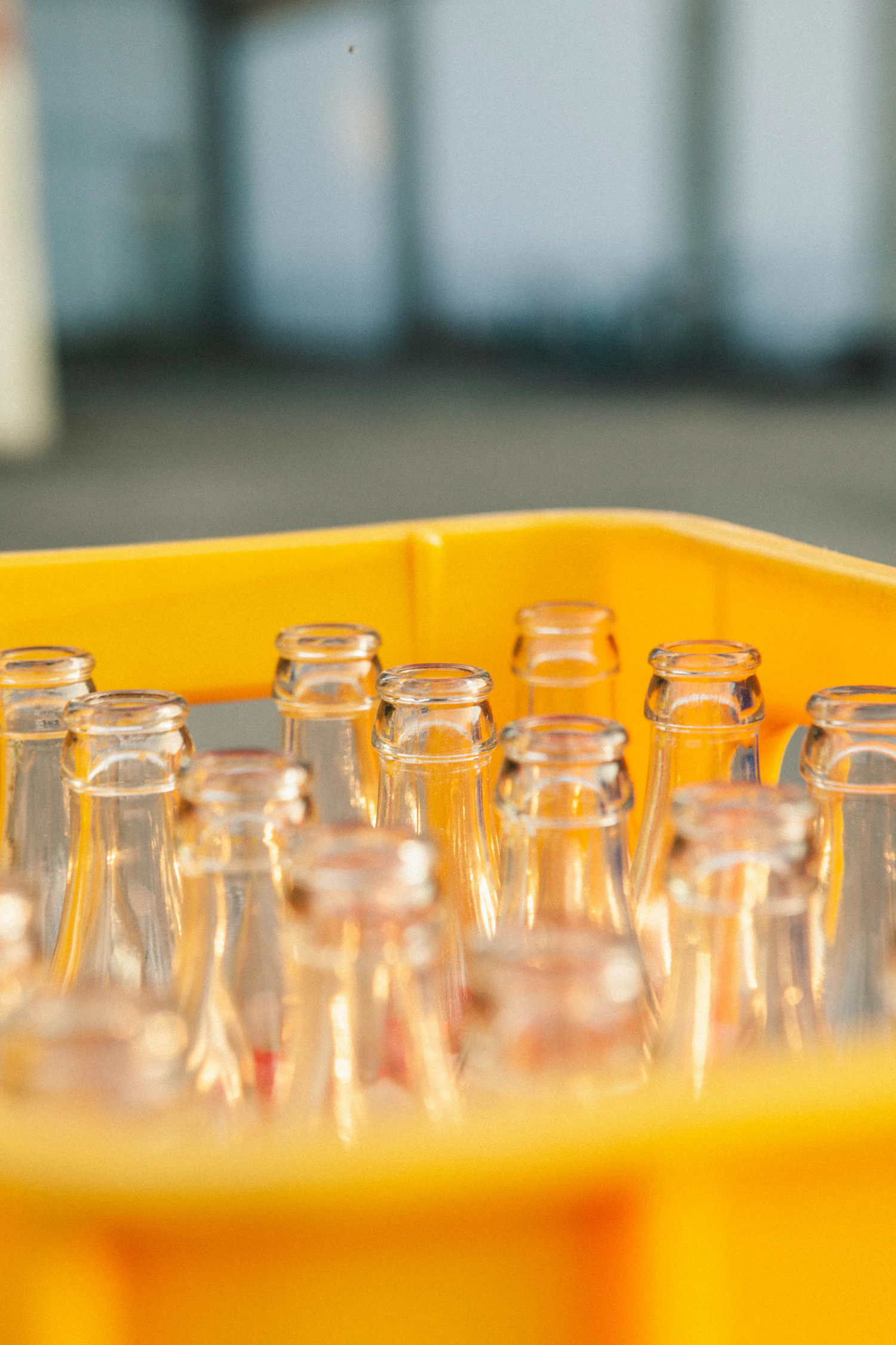 Empty glass soda bottles standing in a yellow bottling crate, ready to be filled