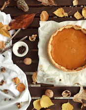 A warm, inviting table set with autumn-themed dishes including roasted turkey, pumpkin soup, and apple tart.