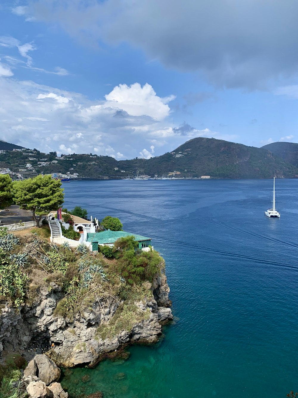 昼間は青い海と白と青の空の下の山に白いヨットを眺める崖の上の家の写真 Unsplashで見つけるイタリアの無料写真