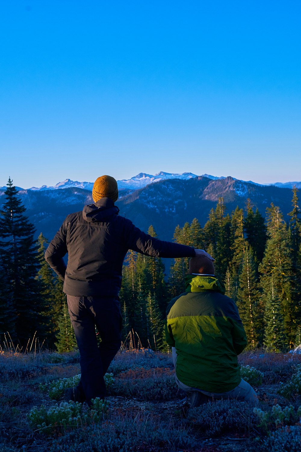 man standing beside man on purple flower field front of mountain