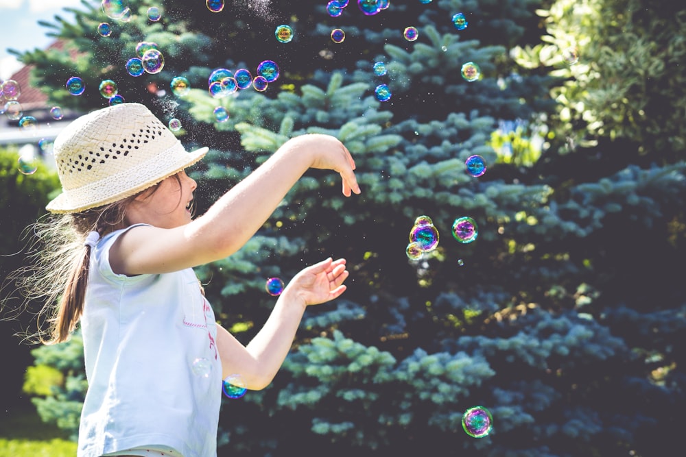 girl playing bubbles near green leaf plant