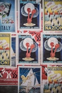 Various vintage posters with colorful and artistic designs are displayed. Central themes include Italy, macaroni, and sailing, with bold graphics and typography.