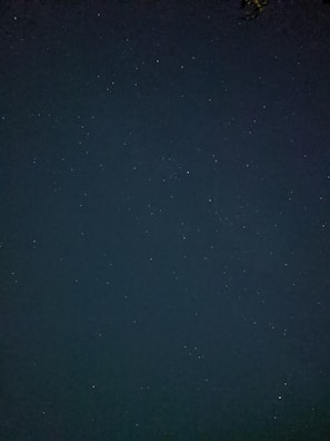A dark midnight blue night sky with twinkling stars, framed by cozy curtains.