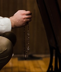 A person holding a rosary with serene sunlight filtering through church windows