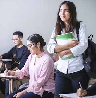 woman carrying white and green textbook