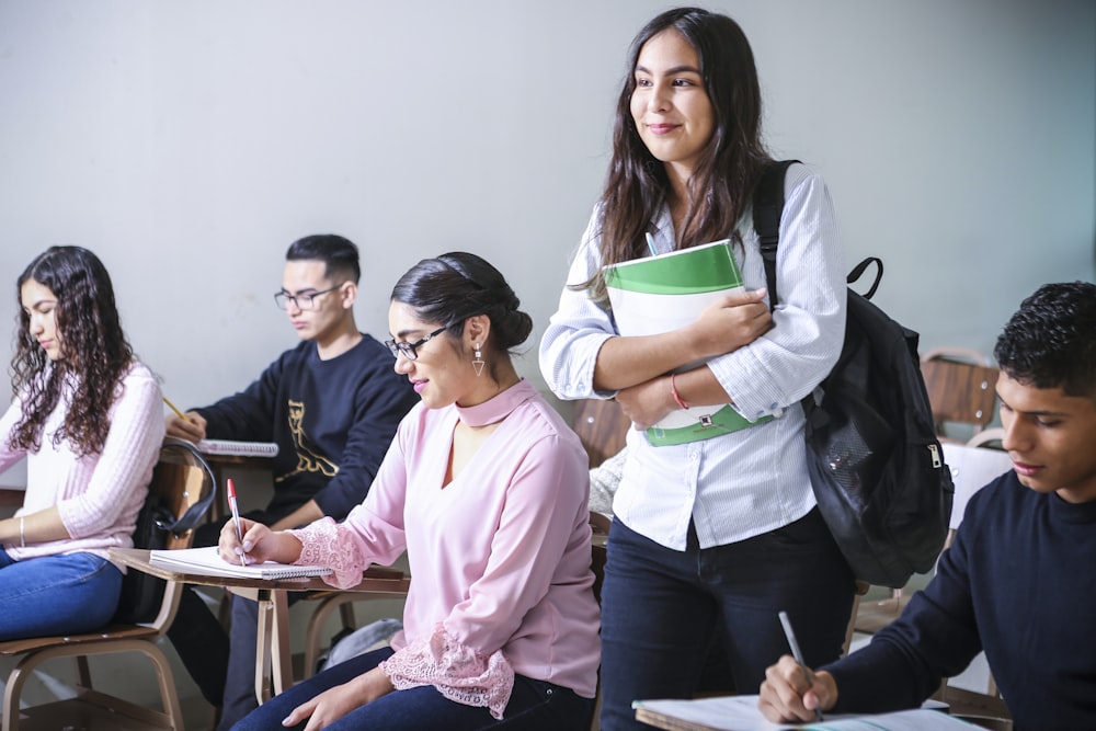 woman carrying white and green textbook