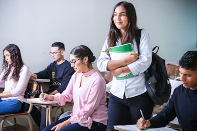 woman carrying white and green textbook student teams background