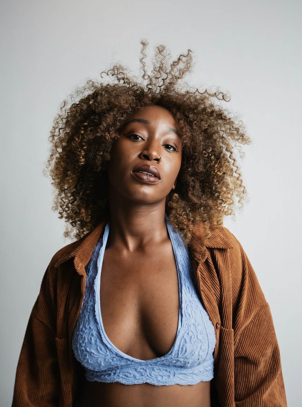 woman wearing blue lace bralette and brown corduroy cardigan