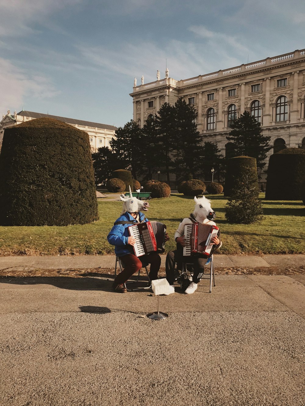 two men playing accordion while sitting in a bench