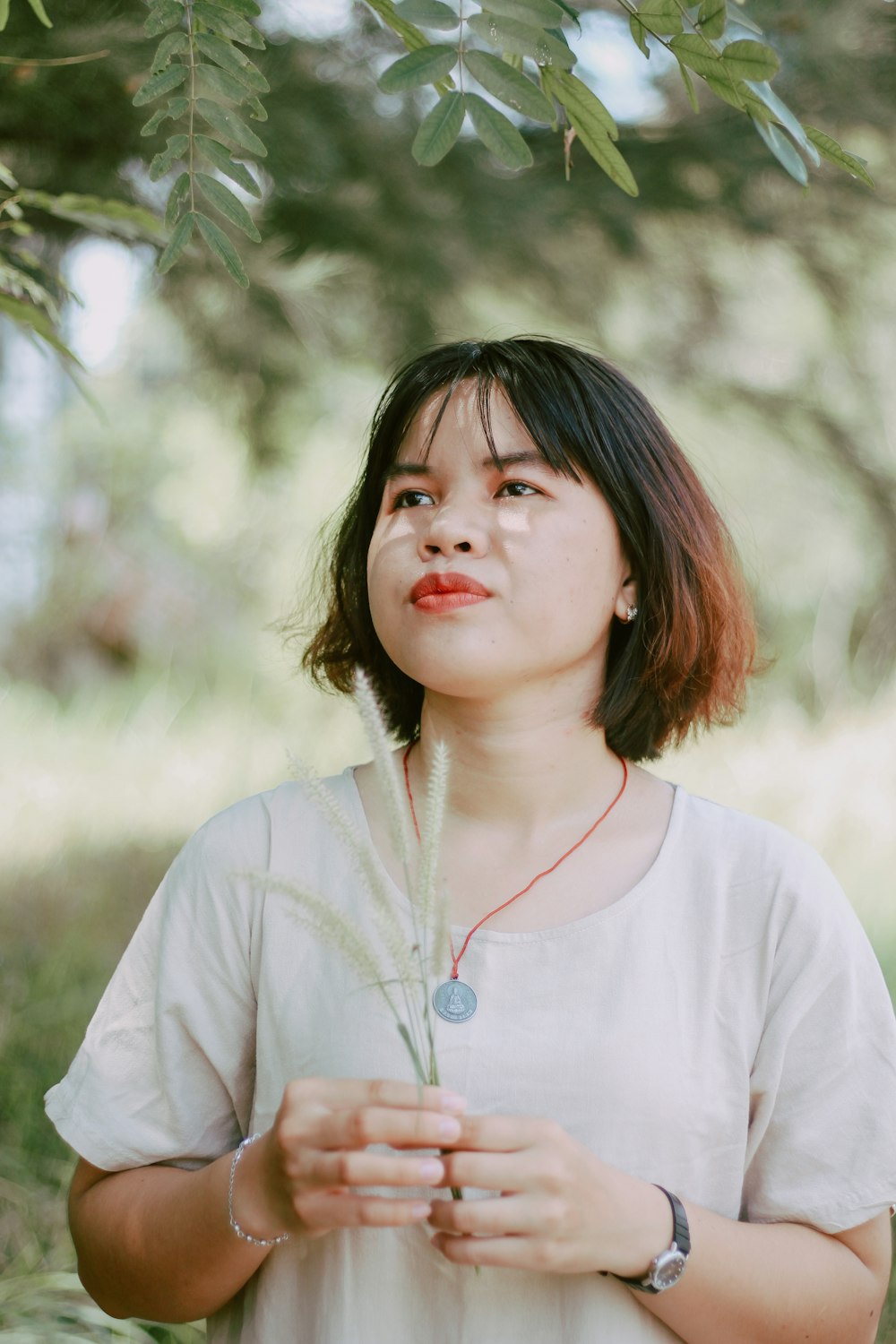 woman in gray crew-neck shirt holding plant