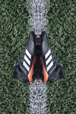 pair of black Adidas cleats on grass field