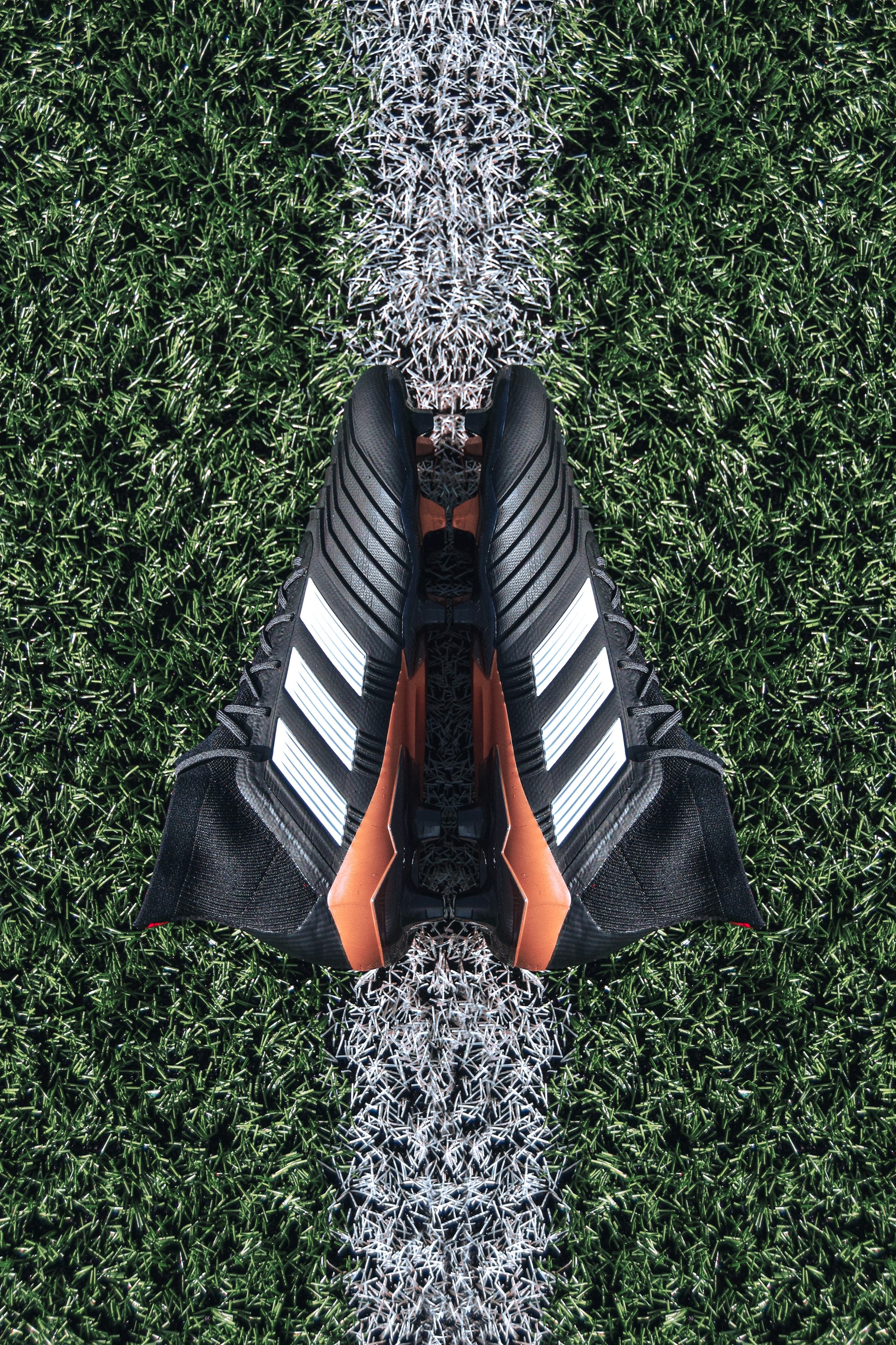 pair of black Adidas cleats on grass field