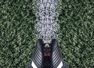 pair of black Adidas cleats on grass field