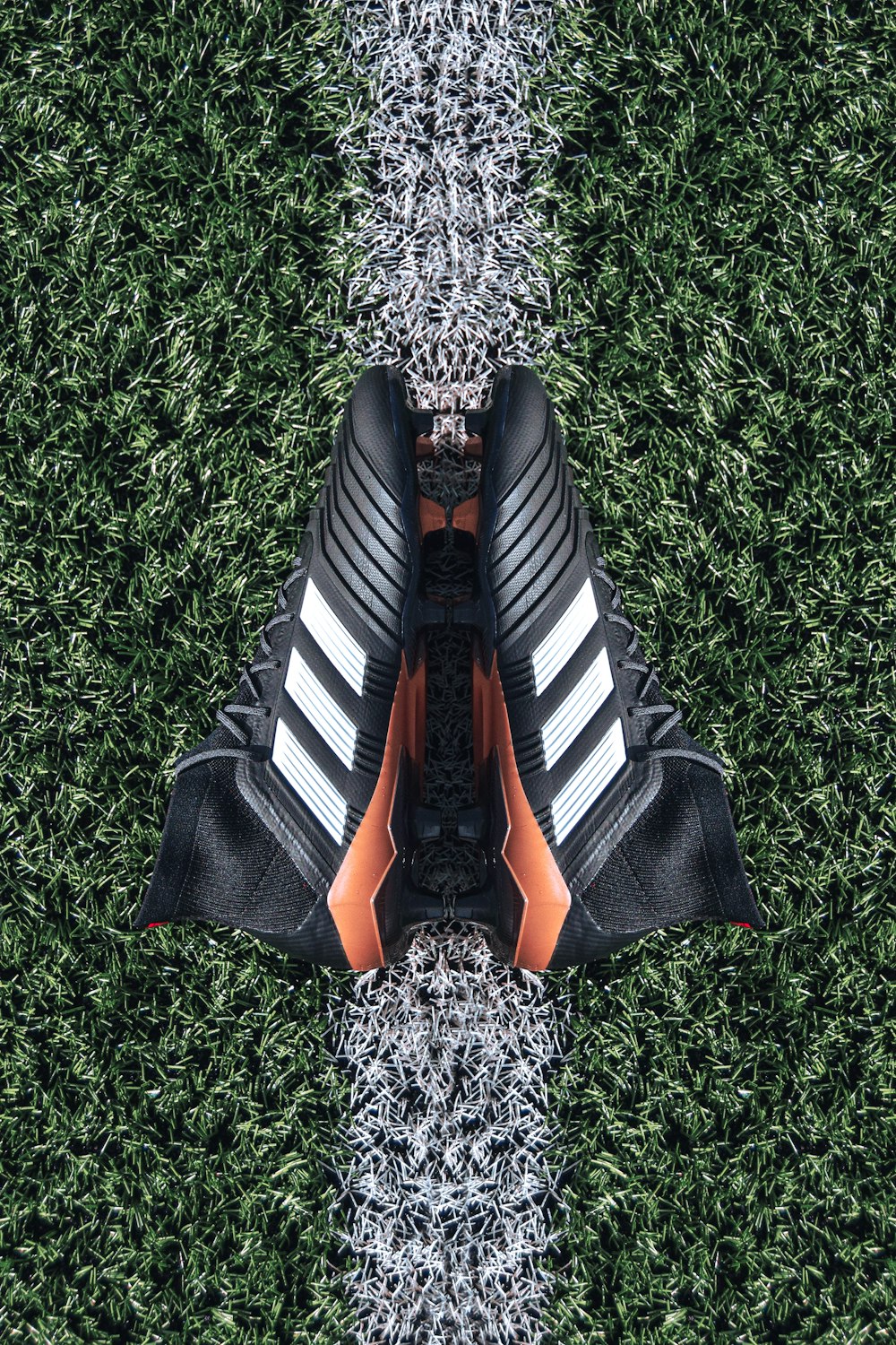pair of black Adidas cleats on grass field