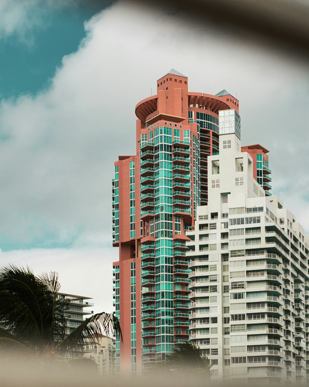 green, white, and brown high-rise building under cloudy sky