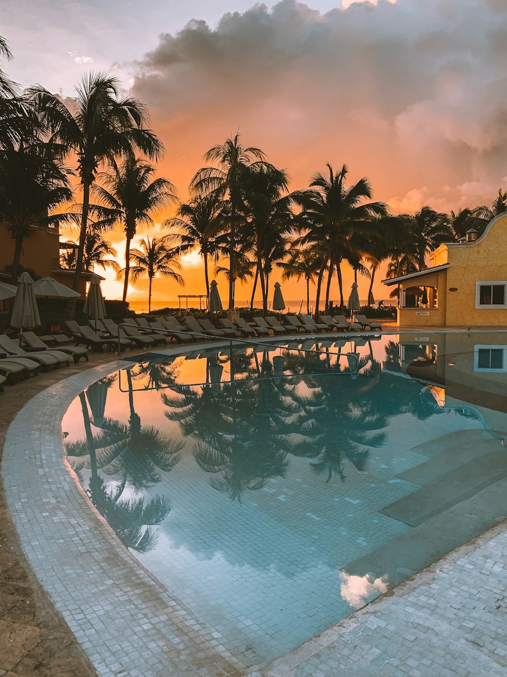 white lounge chairs near outdoor pool during cloudy day