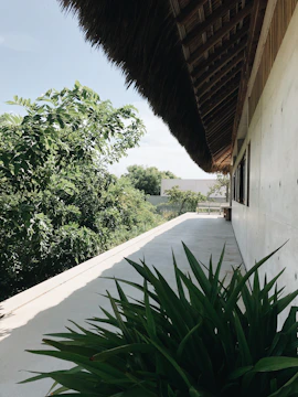 A modern synthetic thatched roof on a stylish outdoor pavilion surrounded by greenery
