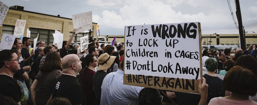 person holding It is WRONG to LOCK UP Children in CAGES sign